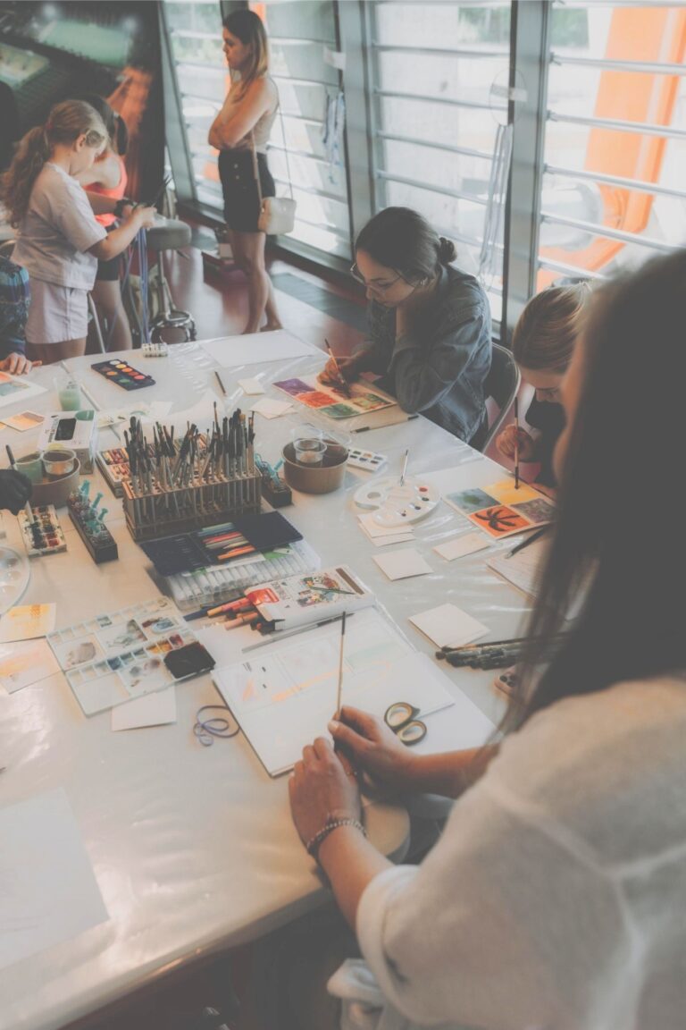 Warsztaty artystyczne w pracowni – uczestnicy malują akwarelami przy wspólnym stole roboczym